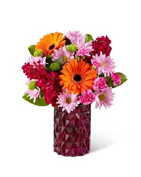 Brightly Bejeweled - Brighten up any springtime occasion with this bouquet that blooms in rich jewel tone colors.This mixed flower arrangement is sure to attract plenty of admiring attention with Gerbera daisies, stock, carnations and roses and more beautifully hand-arranged in a glass vase that sparkles like amethyst colored gemstones. 