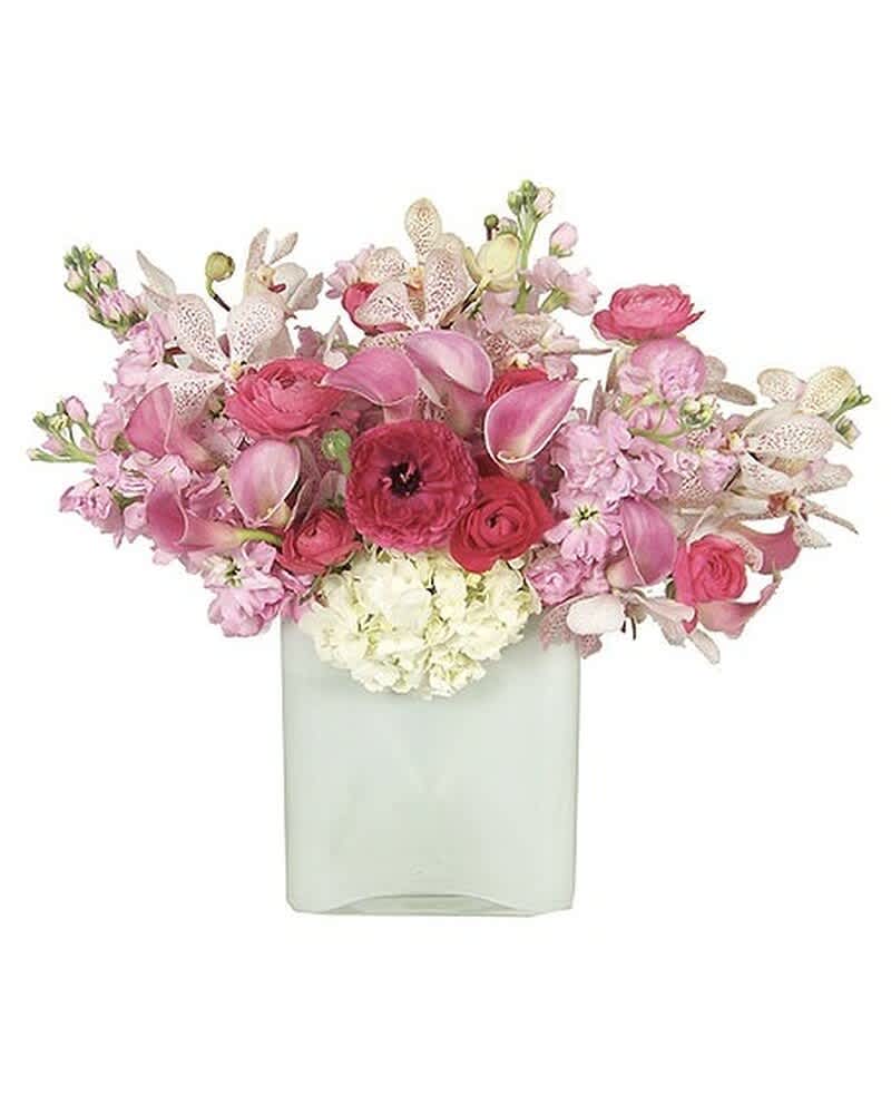 Low arrangement of pink flowers with orchids, calla lilies, and hydrangea in a frosted white cube vase