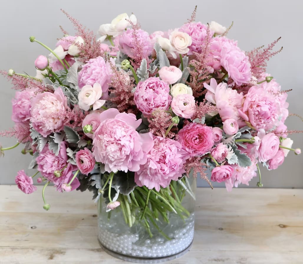 Peony Petals - WeHo  - Peonies are the focal point of this arrangement! We've layered peonies with white and pink ranunculus for a full and lush design, in a glass vase. The picture shown is in the standard size, don't forget to upgrade for more blooms!