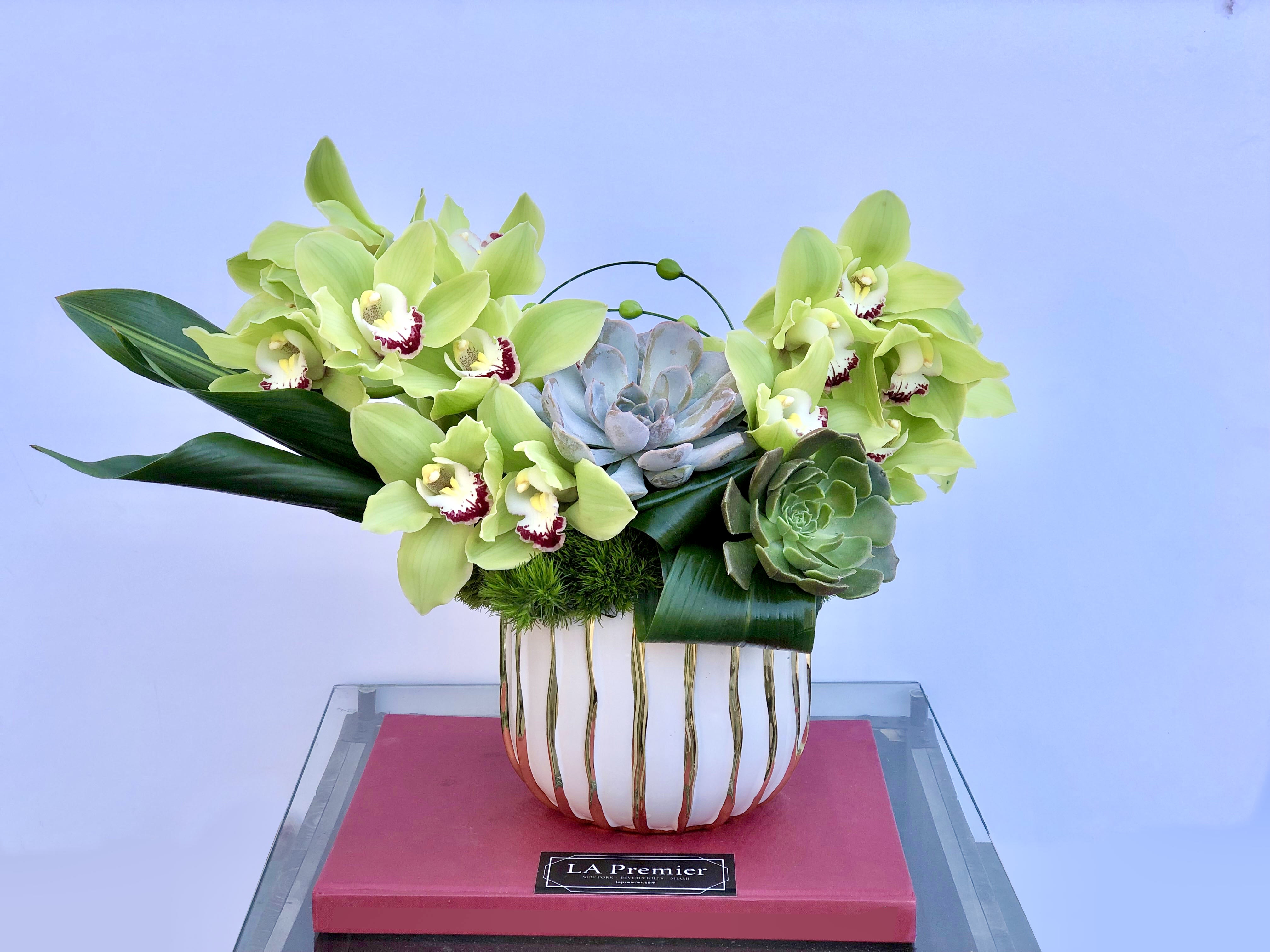 Petit Emerald - Gorgeous green Cymbidiums and tropical leaves are artfully designed to create an ultra-modern and luxurious arrangement, in a perfectly portable size.  vase size: 6x7"  *blooms and vase subject to availability*