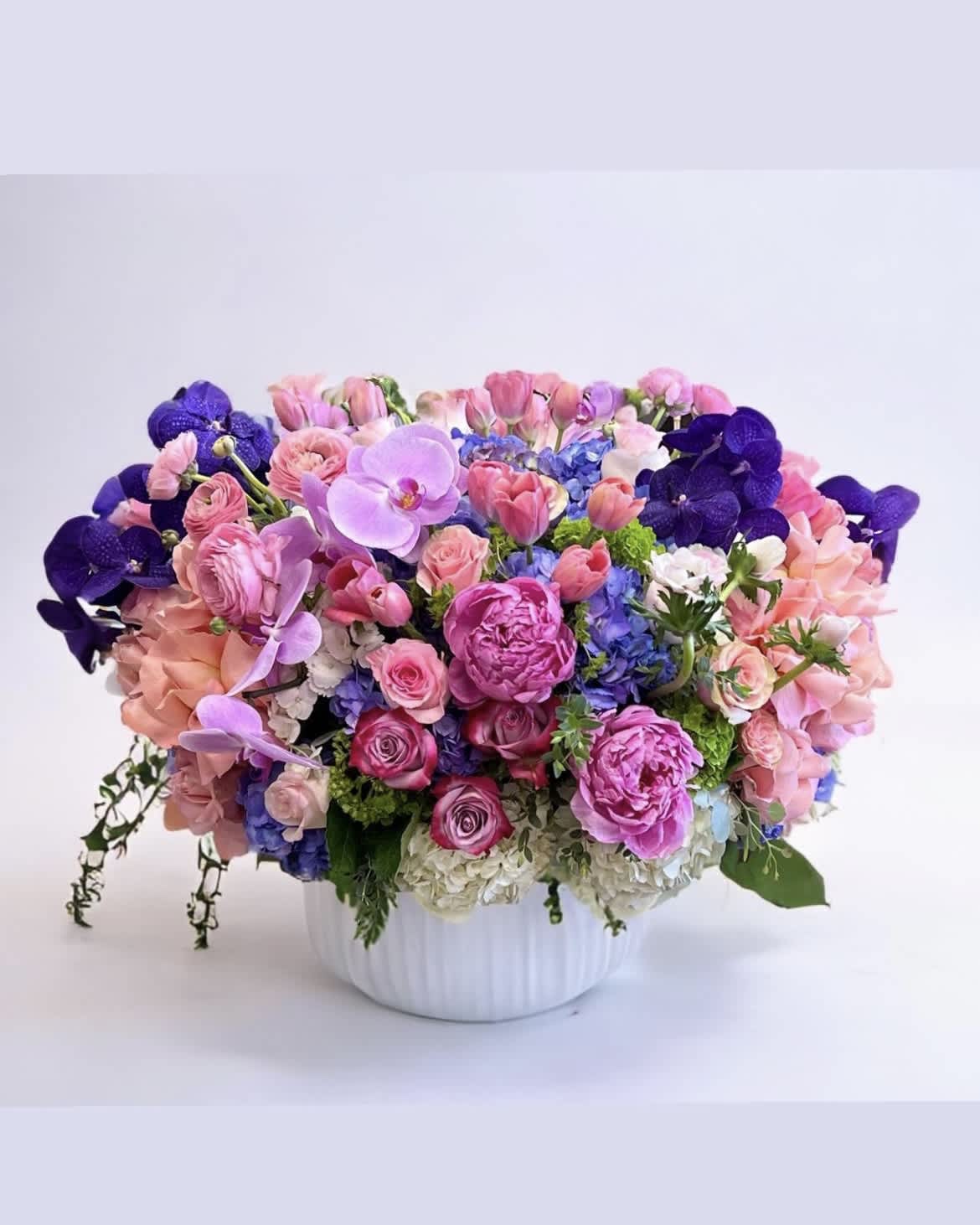 Gregoriano  - Make a statement with this luxurious ceramic vase arrangement! Featuring clusters of soft pink and purple Roses, with pink Ranunculus, Peonies, and Tulips, topped with stunning purple Vanda and Phalaenopsis Orchids