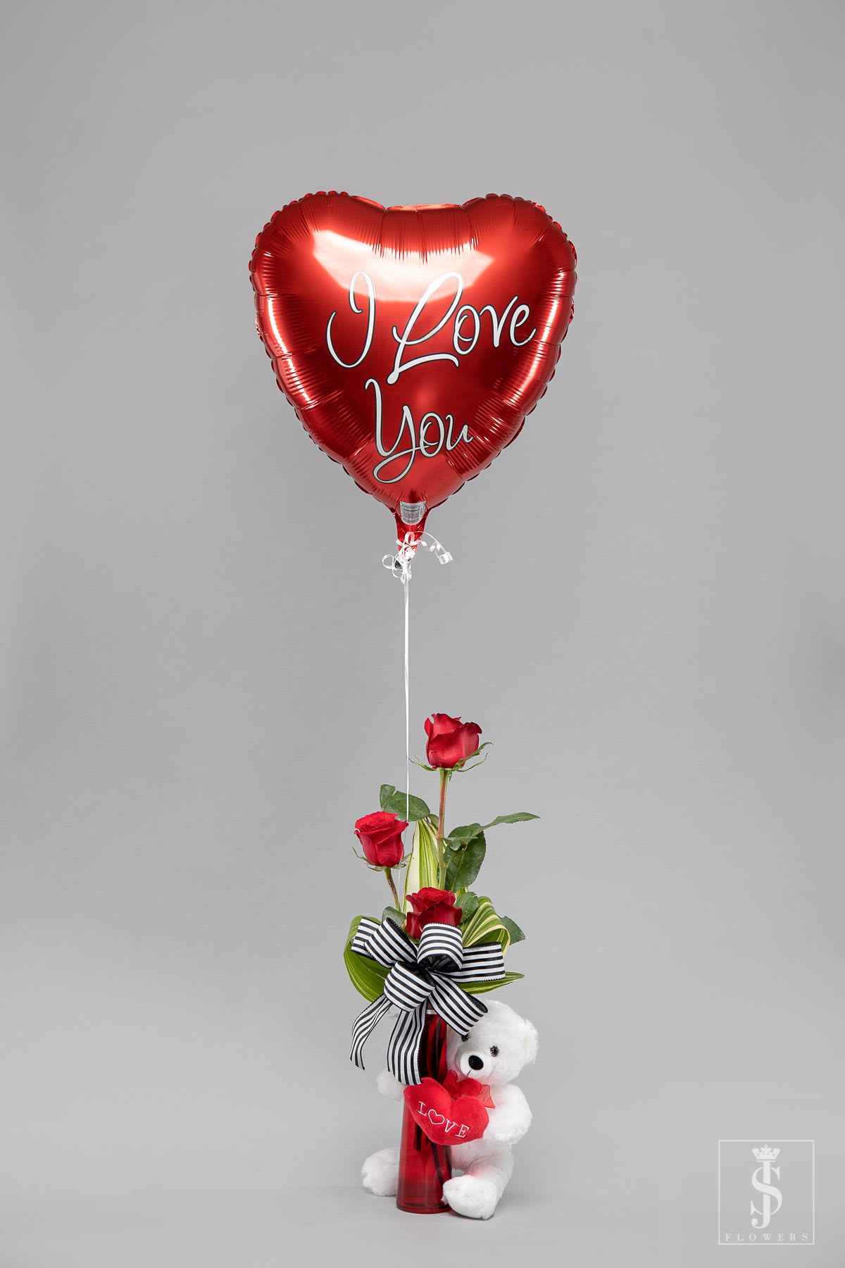Red heart I Love You balloon with three red roses in a red vase and a white teddy bear.
