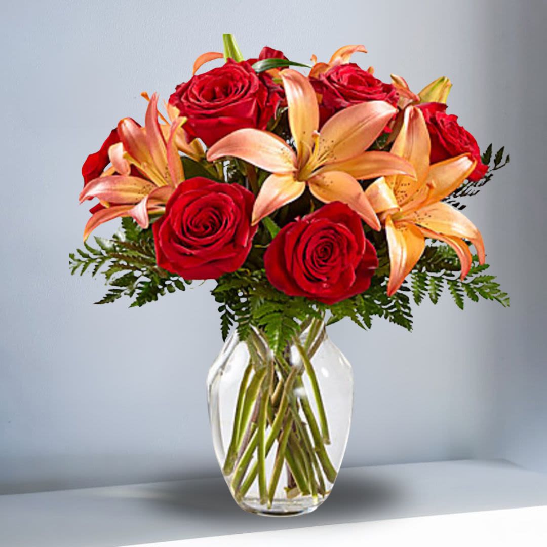 Fireside - This Bouquet blooms with the bold, rich colors of the autumn months to create a warm and unforgettable gift. Rich red roses are paired with orange bi-colored Asiatic Lilies to create a harvest display your special recipient will love. Presented in a clear glass vase , this bouquet glows with gratitude and fall's best hues to create a wonderful thank you, thinking of you, or happy Thanksgiving Day gift. Regular bouquet is approx. 15"H x 13"W. Deluxe bouquet is approx. 15"H x 14"W. Premium bouquet is approx. 17"H x 15"W.