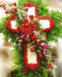 Standing funeral cross of red and white flowers with cascading red blooms on a green foliage base.