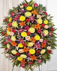 Vibrant Garden Standing Spray - A lively and colorful standing spray designed to celebrate life with a bold and cheerful palette. This multi-hued arrangement features pink Starfighter Oriental lilies, orange Asiatic lilies, bright yellow football mums, red and pink carnations and roses, purple asters, snapdragons, and lush fresh greens. The combination of vibrant blooms and textures creates a full, dynamic, and visually stunning tribute.