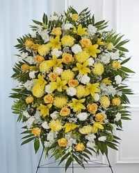 Sunlit Elegance Standing Spray - A bright and graceful standing spray designed to convey warmth, remembrance, and heartfelt sympathy. This elegant tribute features a harmonious blend of yellow roses, white roses, yellow lilies, white stock, white carnations, yellow cremons, solidago, and white asters, artfully arranged with lush greenery for a full and balanced presentation.  The sunny and uplifting combination of yellow and white blooms symbolizes friendship, love, and remembrance, making this arrangement a thoughtful and beautiful way to honor a cherished life. Perfect for display on a standing easel, this floral spray offers a dignified and comforting tribute.
