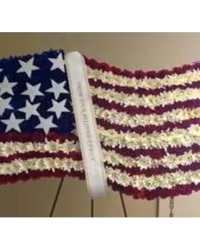 Waving American flag design made of red, white, and blue flowers on a standing easel.