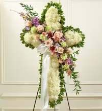 Eternal Pastel Cross Spray - A graceful and heartfelt standing cross arrangement, thoughtfully designed to convey sympathy and honor. The solid cross of chrysanthemums is lined with lush fresh greens and features a soft floral break in pastel tones, including roses, mums, and carnations. This elegant design combines traditional symbolism with a gentle, comforting color palette, creating a beautiful tribute for any occasion.