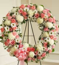 Sweet Memories Standing Wreath - A soft and graceful pink and white standing wreath designed to honor and remember a cherished life. This elegant tribute features white cremon mums, pink carnations, white asters, white daisies, baby’s breath, spray roses, mini carnations, and white cushion mums, beautifully arranged with fresh greenery.  Finished with a pink ribbon bow, this wreath symbolizes love, compassion, and remembrance, offering a heartfelt and comforting expression of sympathy for funeral or memorial services.