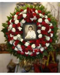 Red &amp; White Remembrance Wreath - A classic red and white funeral wreath designed to surround and honor a cherished photograph. This elegant tribute features red and white carnations accented with delicate baby’s breath and fresh greenery, creating a timeless and meaningful display of sympathy and remembrance.  Designed to frame a memorial photo, this arrangement offers a beautiful way to celebrate and honor a loved one’s memory. Frame and photograph are not included.