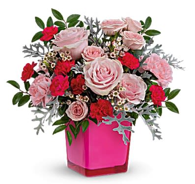 Pink and red rose and carnation arrangement in a bright pink cube vase