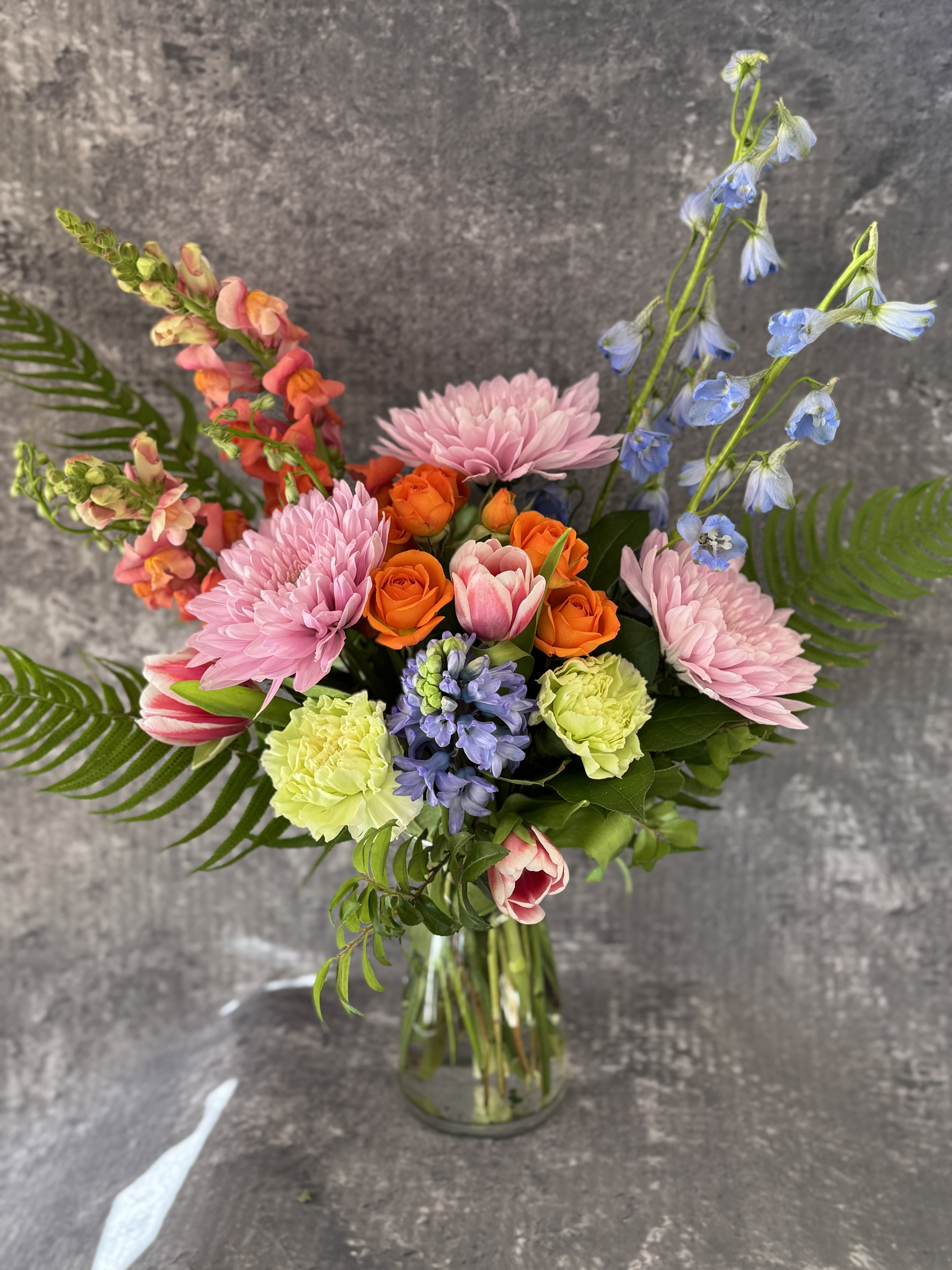 Mixed bouquet in a glass vase with pink, orange, and blue flowers
