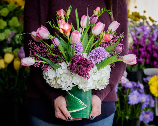 Pink tulips and purple flowers arranged in a green vase