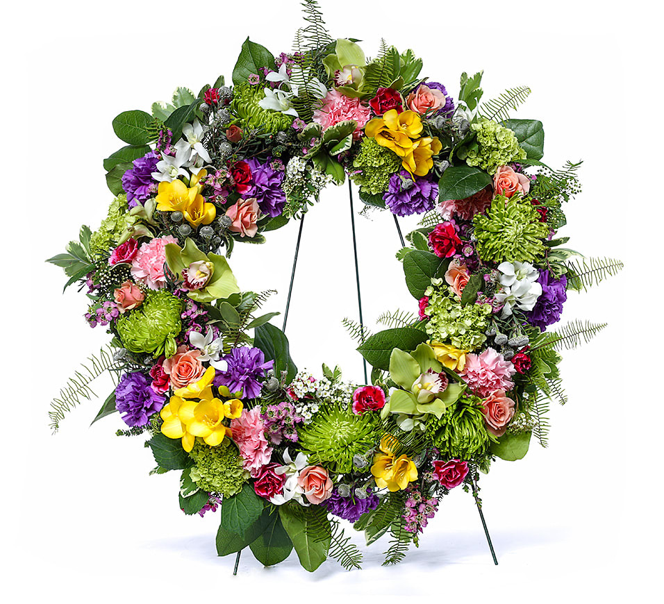 Colorful mixed flower wreath with roses, orchids, mums, and carnations on a metal stand