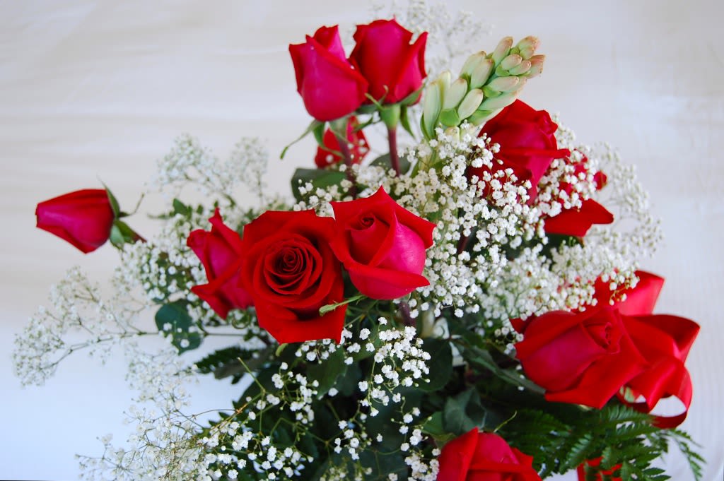 Special Rose Bouquet - Lush clusters of open and budded red roses create a classic romantic bouquet-perfect as a birthday bouquet, anniversary roses gift, or simply to say "I love you." The vivid red blooms pop against airy white filler flowers for a bold, elegant contrast that makes the recipient feel deeply seen and celebrated.  Hand-tied with a red ribbon at the base, this arrangement balances rich texture and refined simplicity. Sizes are a generous hand-tied style; stems are arranged to sit naturally in a vase (vase not included). For best enjoyment, trim stems and change water every other day to keep the roses fresh and fragrant-an effortless way to extend the moment.