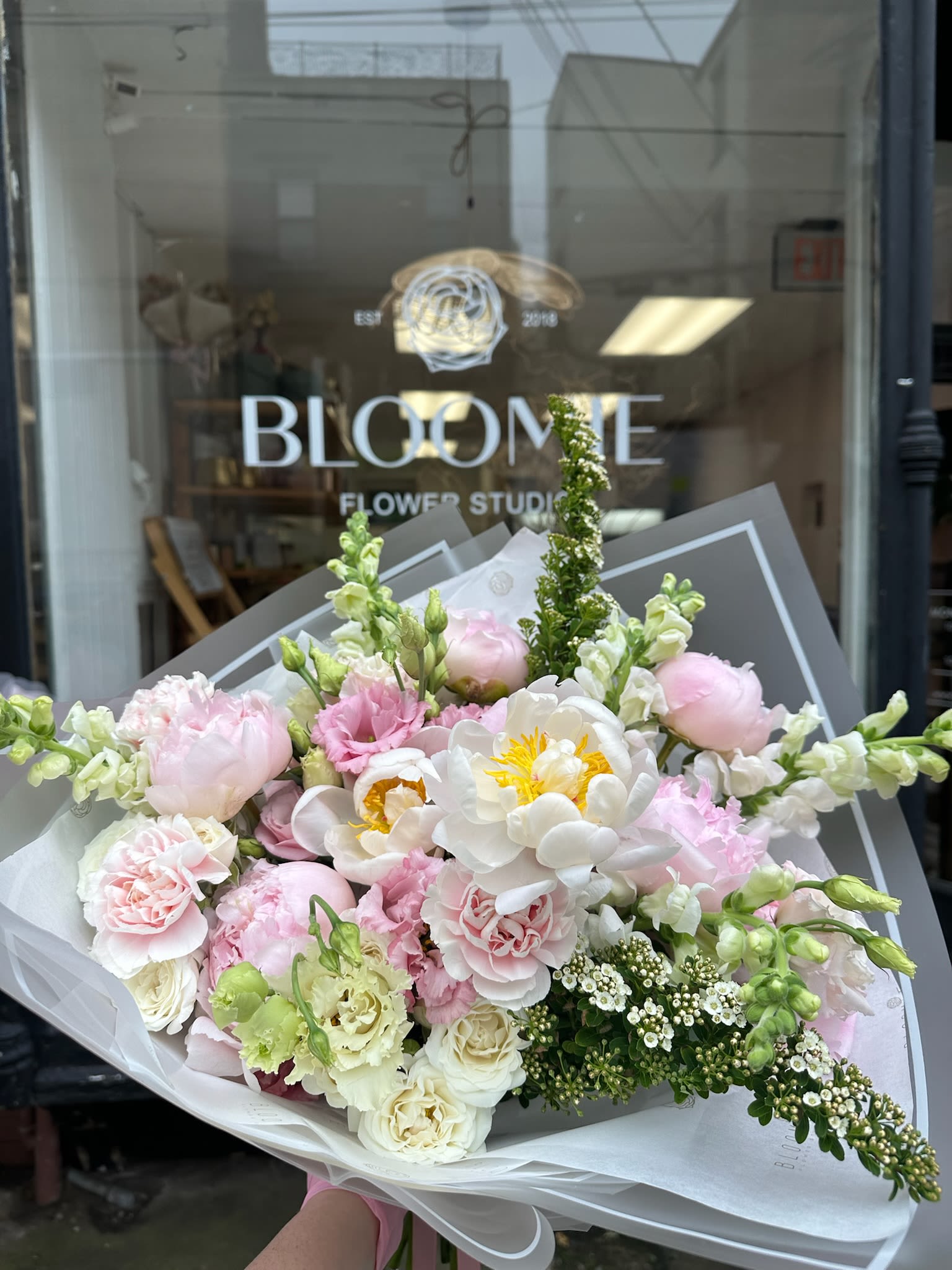 Peony Cloud - A lush, garden-style bouquet featuring soft pink peonies, garden roses, snapdragons, and delicate seasonal blooms in blush, cream, and fresh green tones. Wrapped in signature Bloomie style, this airy and romantic arrangement is perfect for everyday gifting, celebrations, or bringing an elegant, garden-inspired feel to any space.