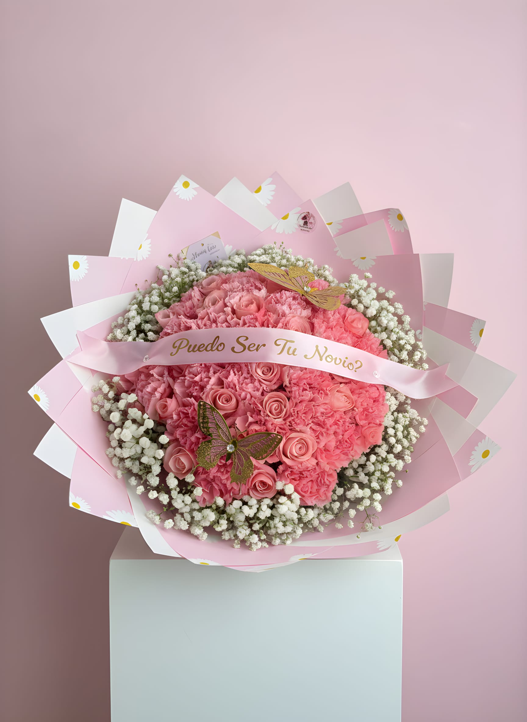 Puedo Ser Tu Novia Proposal Pink Roses &amp; Carnations - Make your moment unforgettable with this dreamy, heart-shaped bouquet designed for one of life’s most special questions. Featuring a lush arrangement of soft pink roses and carnations, delicately surrounded by baby’s breath and wrapped in elegant Korean-style paper, this piece is finished with a personalized ribbon that reads “¿Puedo Ser Tu Novio?” for the perfect romantic touch.  A stunning way to express your feelings and create a memory they’ll never forget.   Perfect for: • Proposals &amp; romantic gestures • Anniversaries • Special surprises  Please note: Flower tones and details may vary slightly depending on availability while maintaining the same overall design, color palette, and style.