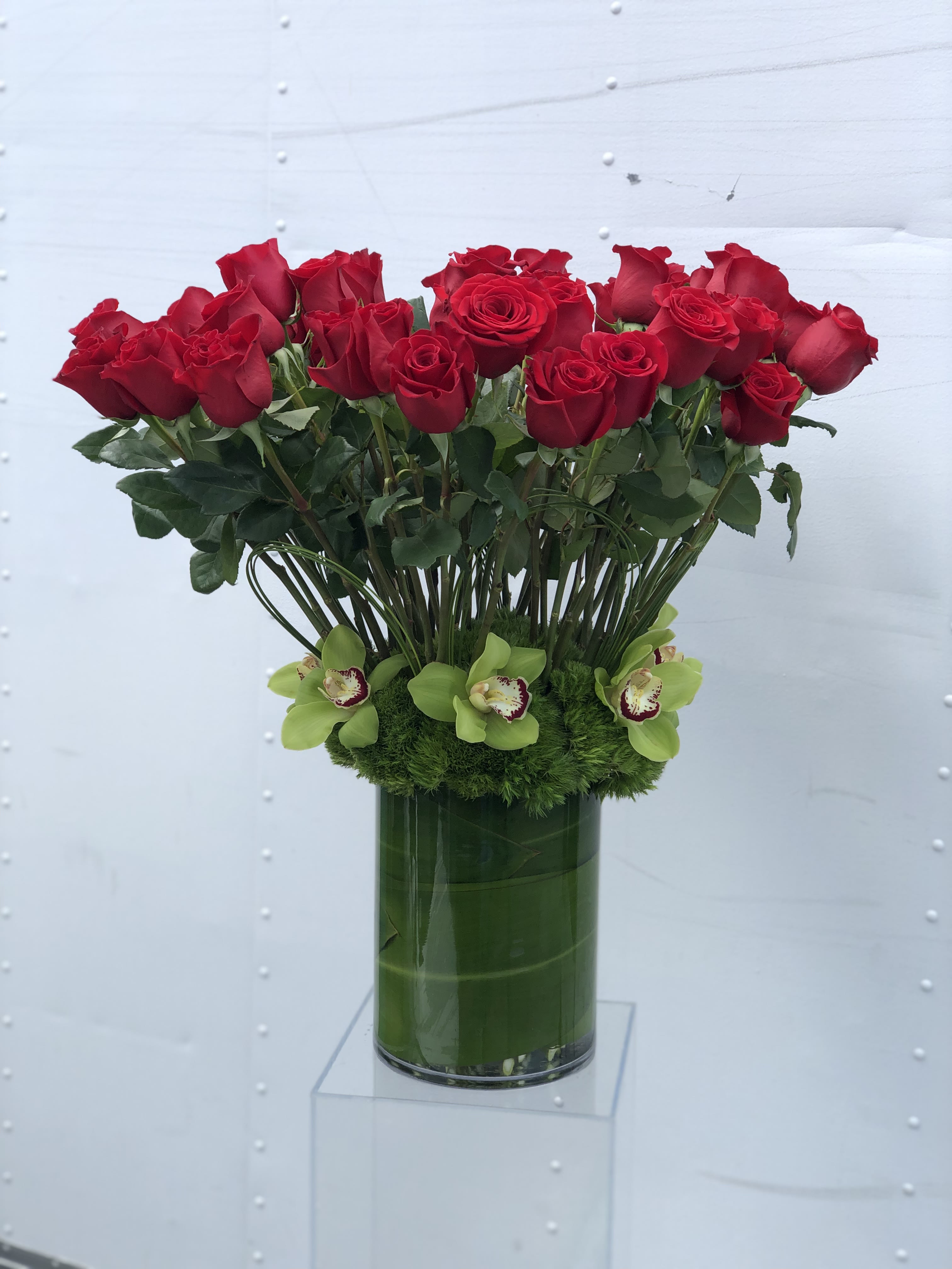 Faithful - Make a statement of love with this beautiful arrangement of 50 red Roses and green Cymbidium Orchids surrounded by Dianthus