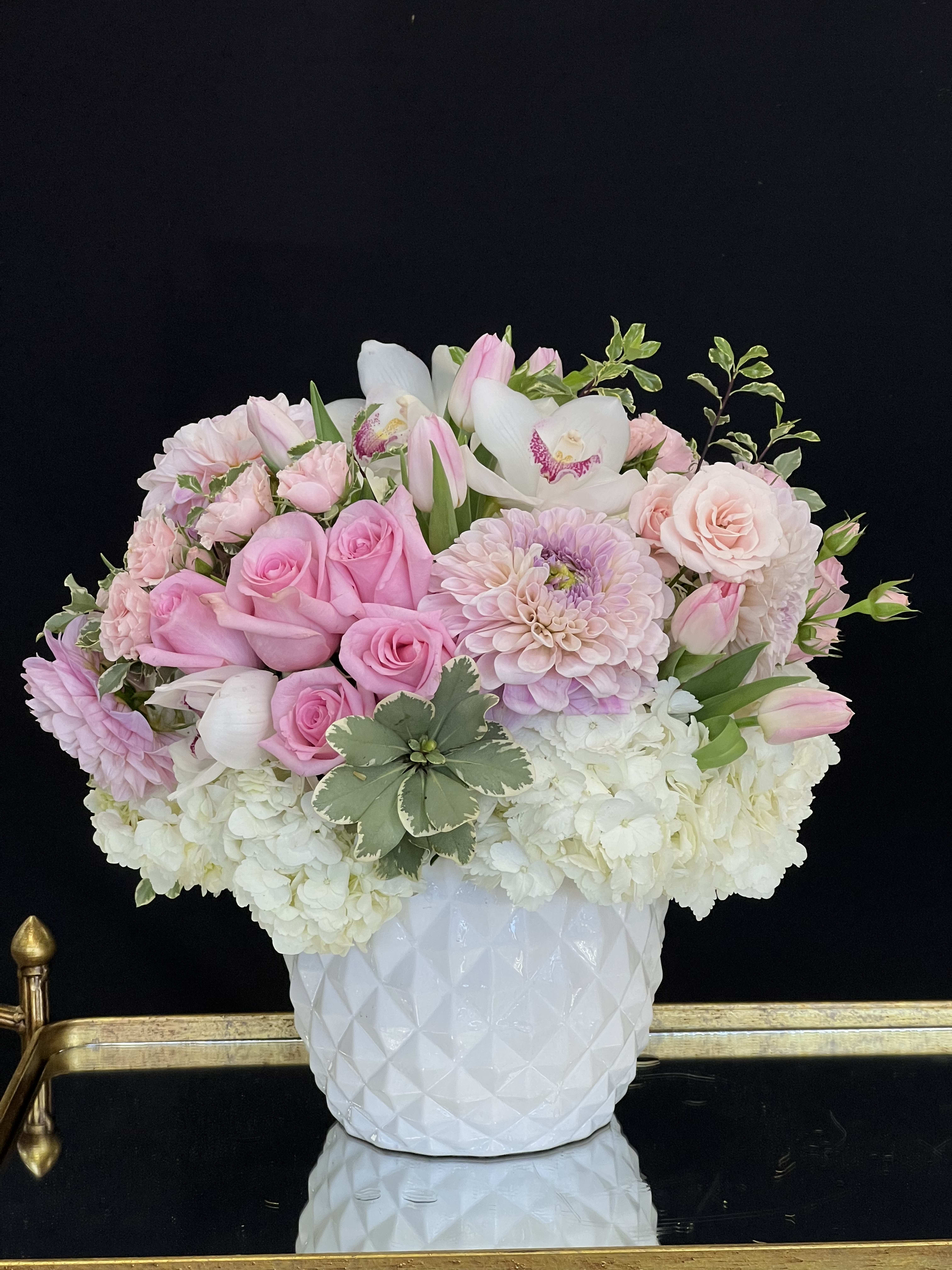 Elena - This pretty white and blush floral arrangement features Roses, Tulips, Dahlias, Spray Roses, and Cymbidium Orchids, with white Hydrangea and select greenery in a patterned ceramic vase