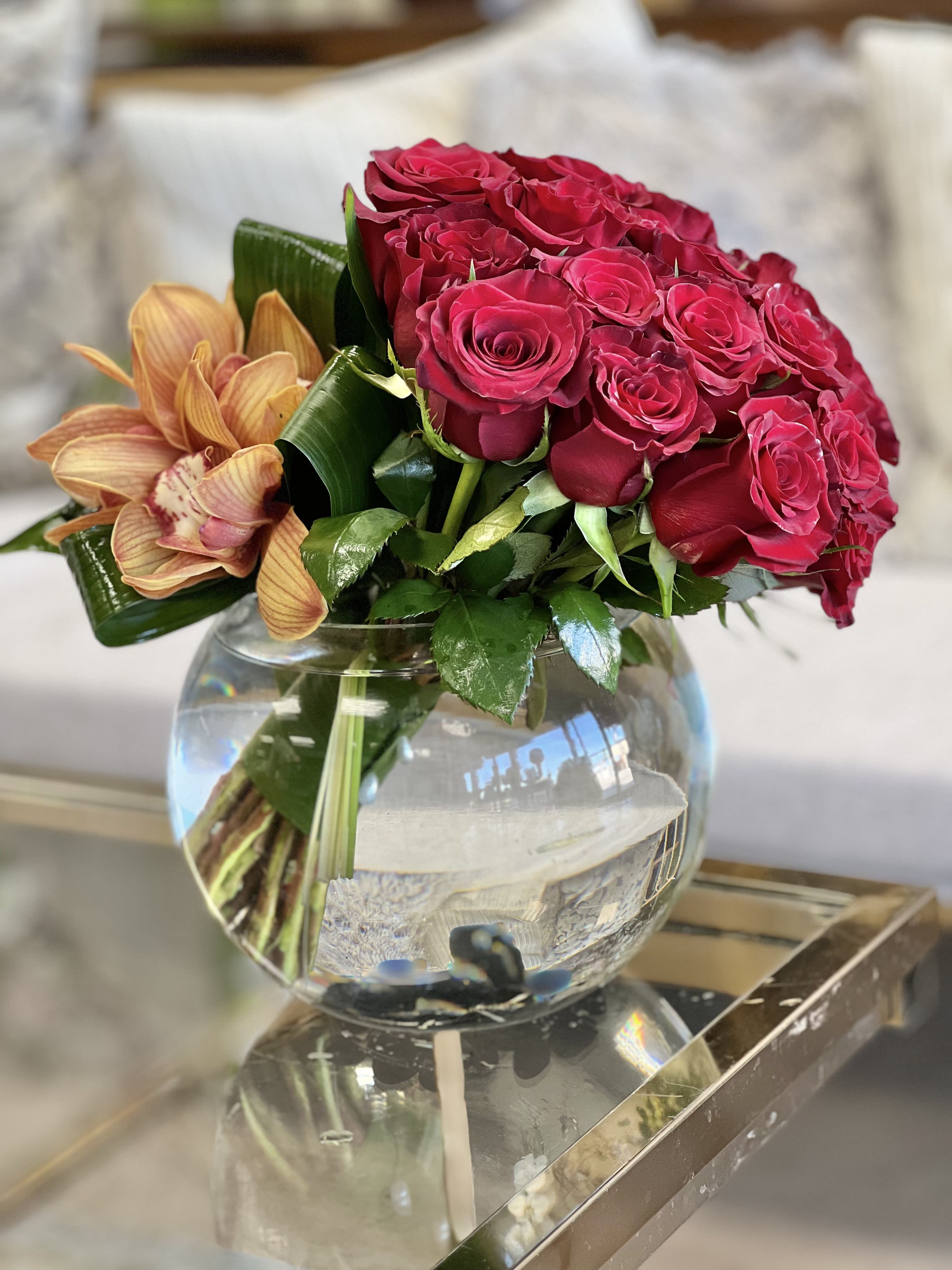 Simple Red - A tight cluster of red Roses, accented with Cymbidium Orchids and set in a bubble bowl vase