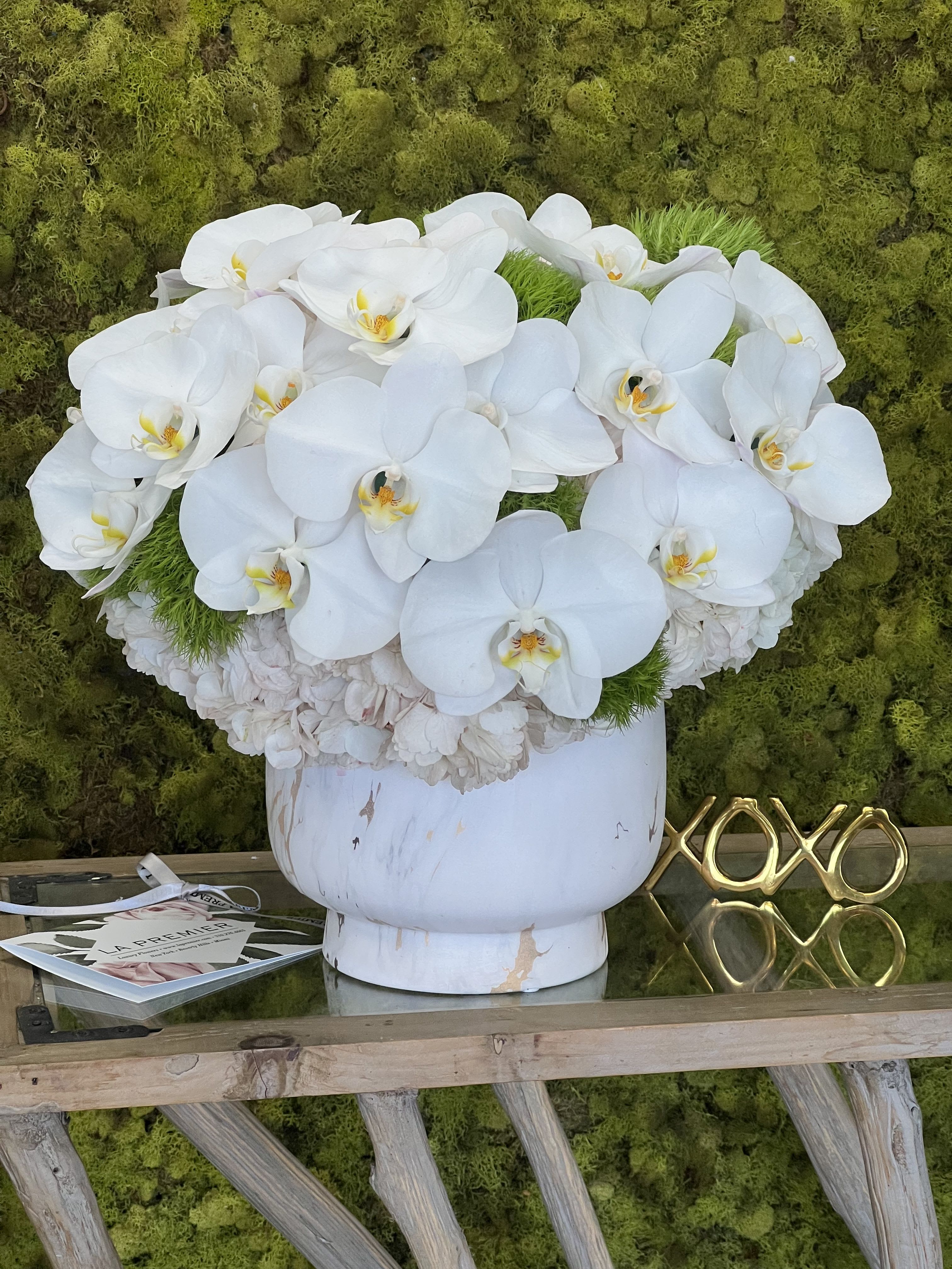 Marine - An abundance of white Phalaenopsis Orchids, interspersed with green Trick Dianthus, with white Hydrangea in a ceramic vase