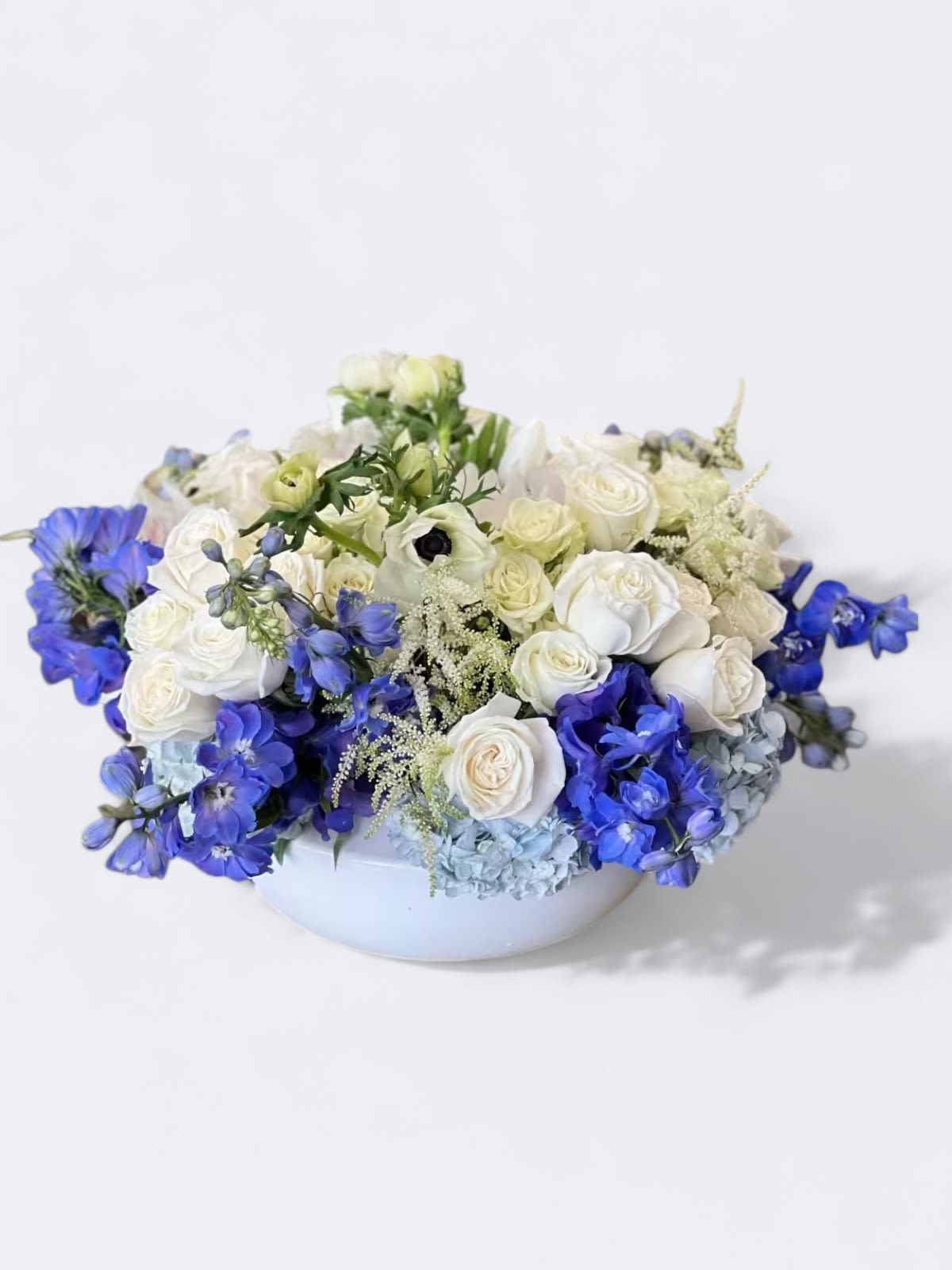 Cielo Azul  - A gorgeous mix of blue and white blooms, including Delphinium, Roses, and Anemones, arranged in a low container