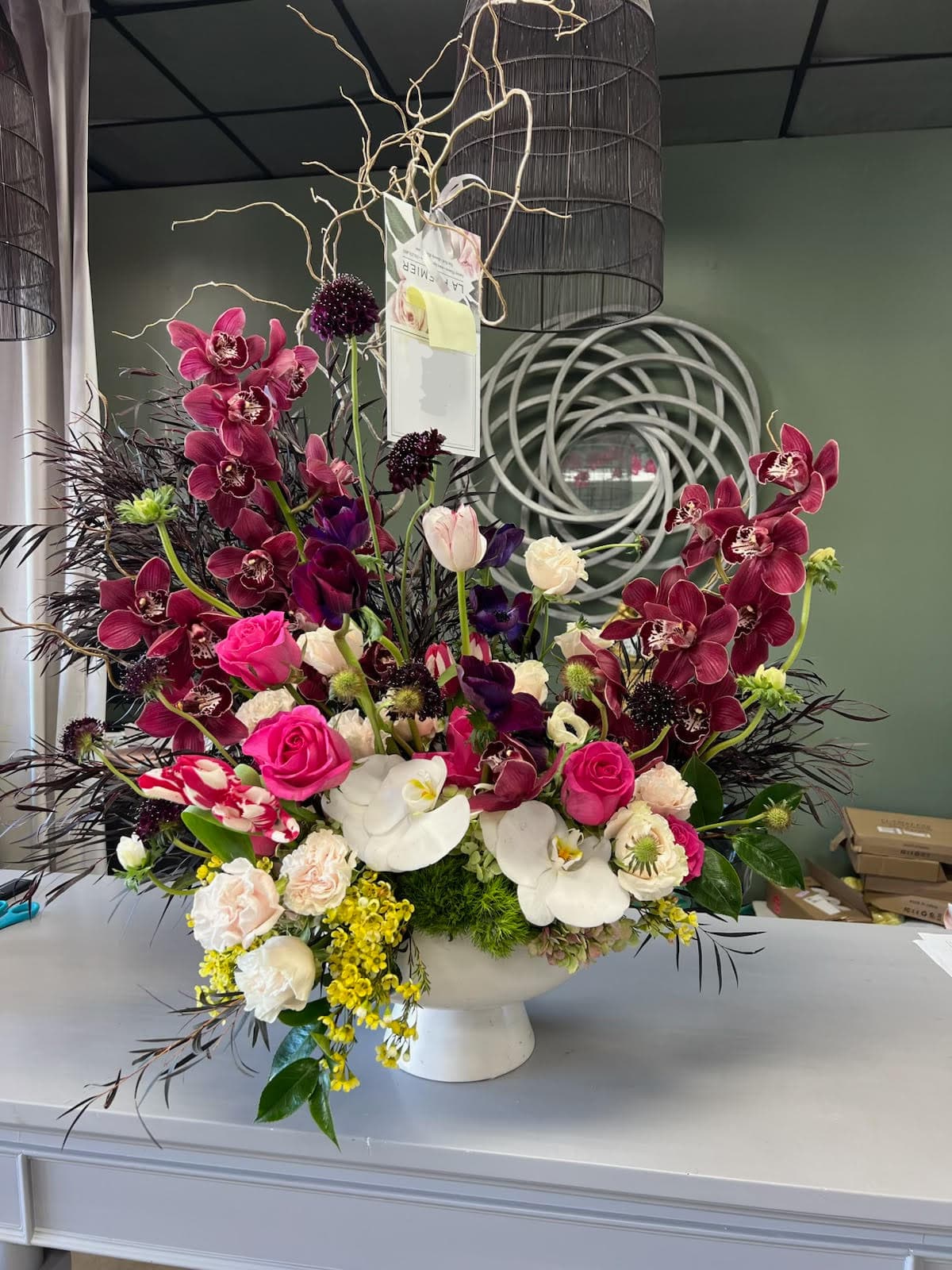Mad Artist - A dramatic and glamorous arrangement of mixed Orchids, Roses, Tulips, and seasonal branches 