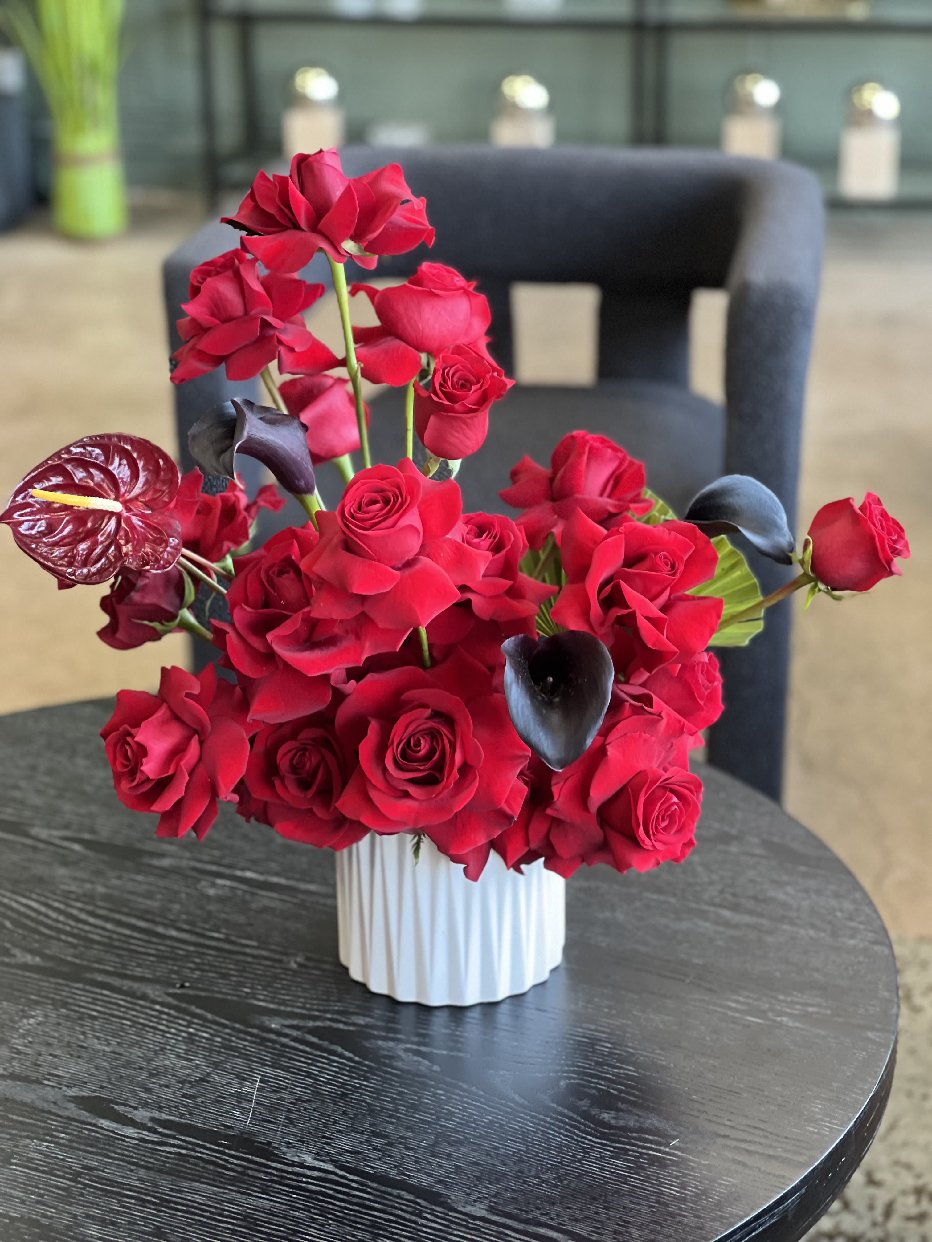 Alina - A stylish, modern arrangement of reflexed red Roses, red Anthurium, and rich black Calla Lilies in a ceramic vase