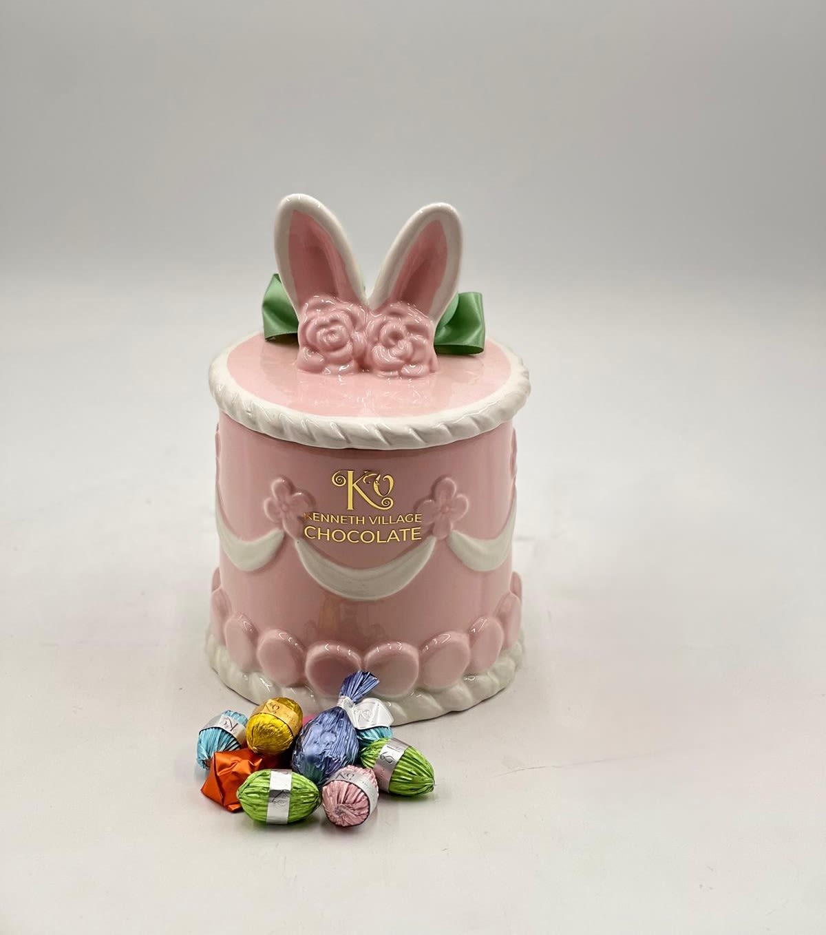 Bunny Chocolate Box - A soft and elegant keepsake, this ceramic container is beautifully detailed with delicate embossed patterns and crowned with charming bunny ears adorned with subtle floral accents. Finished with a gentle green ribbon, it opens to reveal a selection of premium wrapped chocolates in cheerful pastel tones. Both decorative and functional, this makes a memorable gift long after the chocolates are enjoyed.