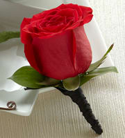 Single red rose boutonniere with black wrapped stem on a white surface