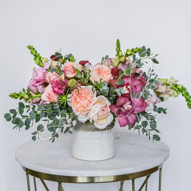 Pink and peach floral arrangement in a white vase
