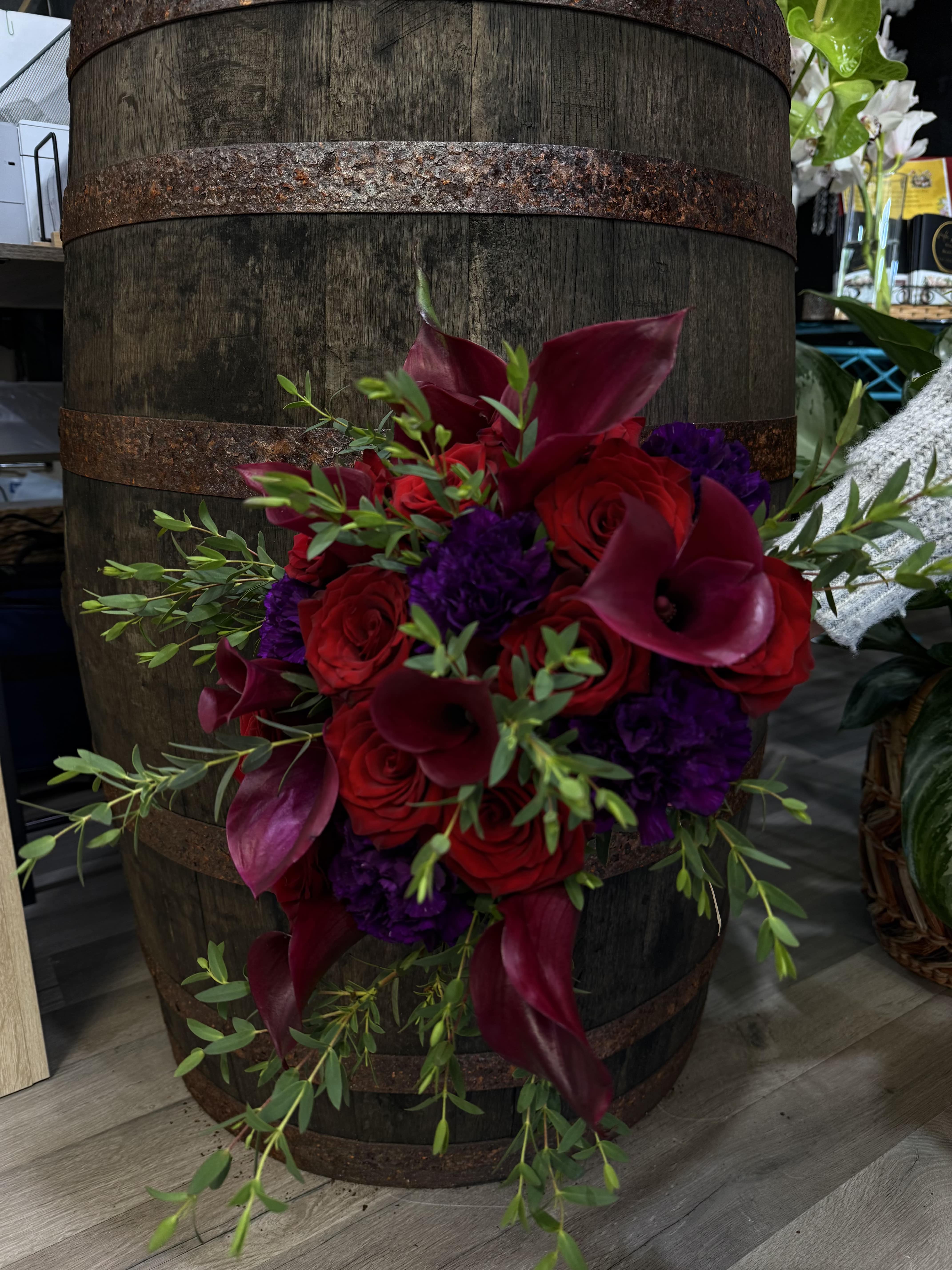 Midnight Romance - A moody, high-contrast bouquet with velvety red roses and striking purple calla lilies, finished with black ribbon or accents. Sophisticated and unforgettable.