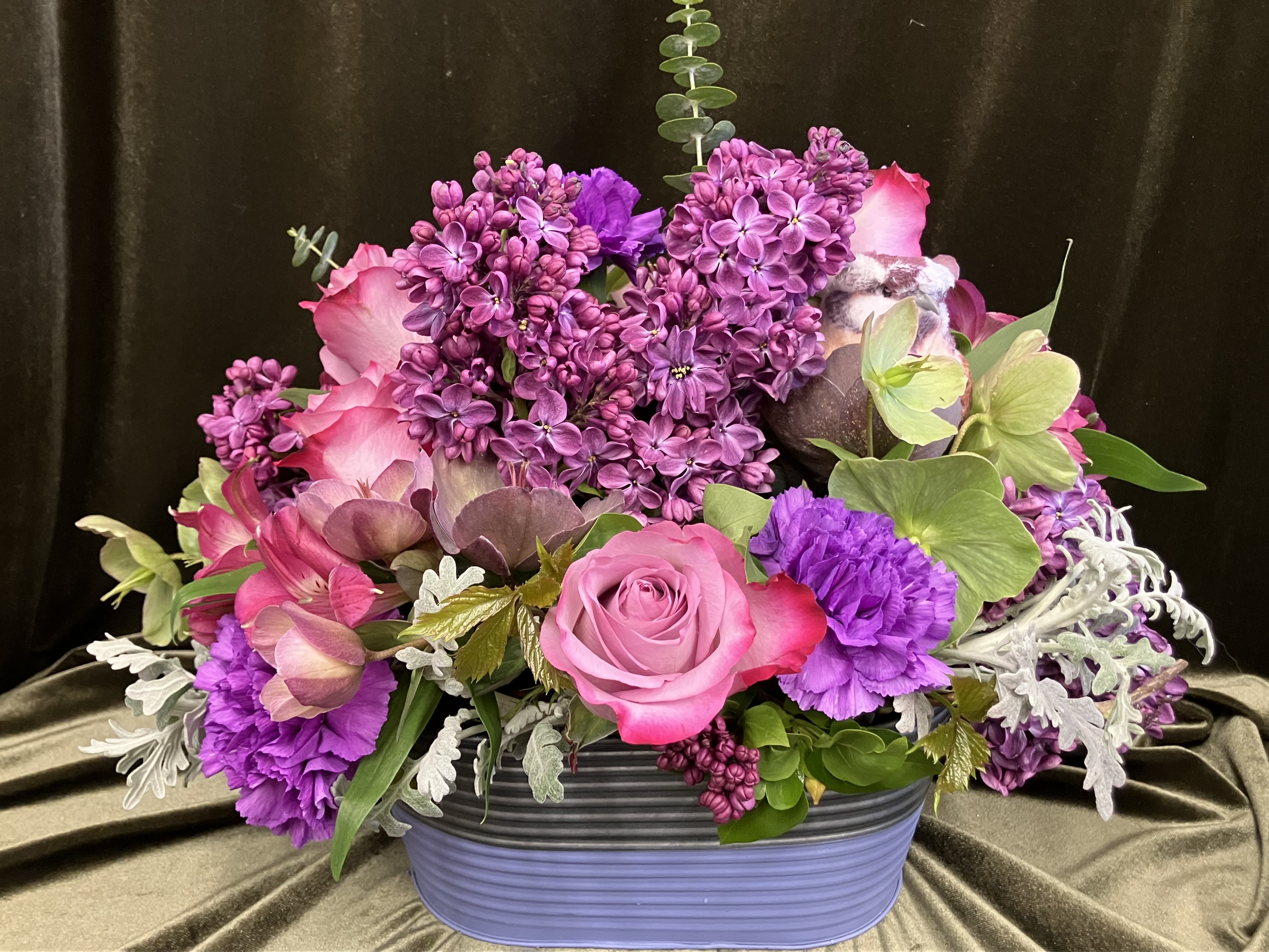 Spring Tin with Lilacs - Oval shaped tin container filled with purple flowers including local lilacs, hellebores, dusty miller, carns and roses 