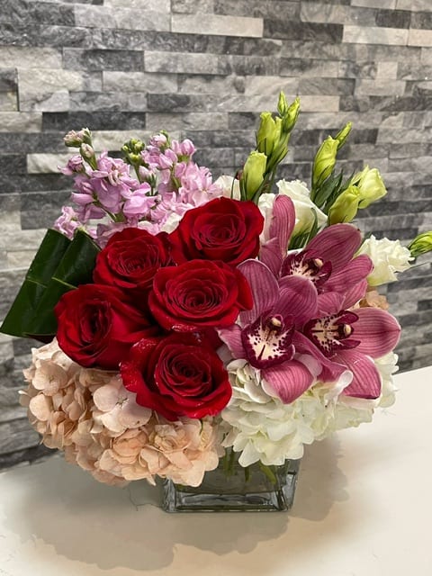 Sammy's Sweetheart - A lush compact arrangement using red roses, hydrangeas, stock and cymbidium orchids.
