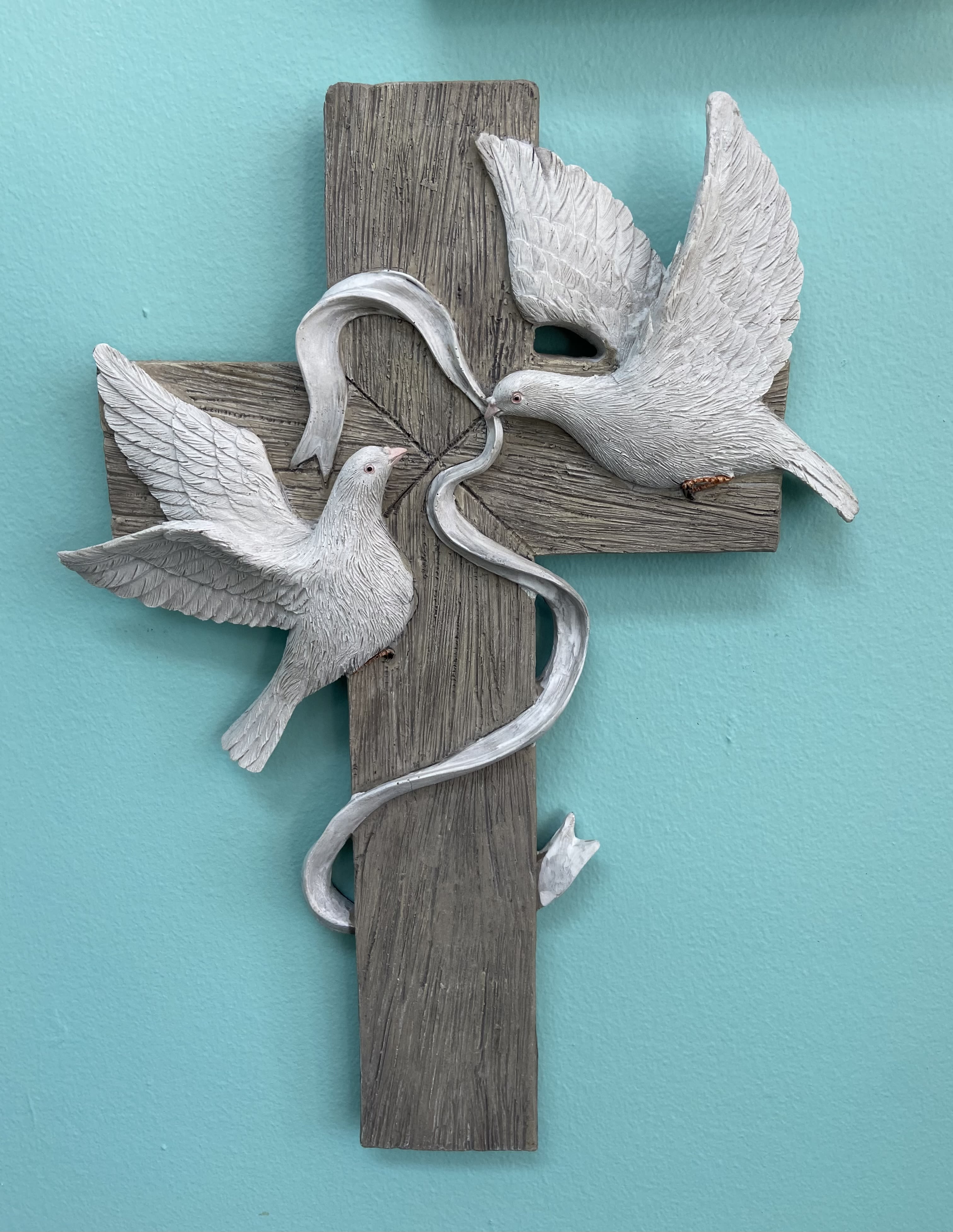 Wood-look cross wall plaque with two white doves and a flowing ribbon on a teal background