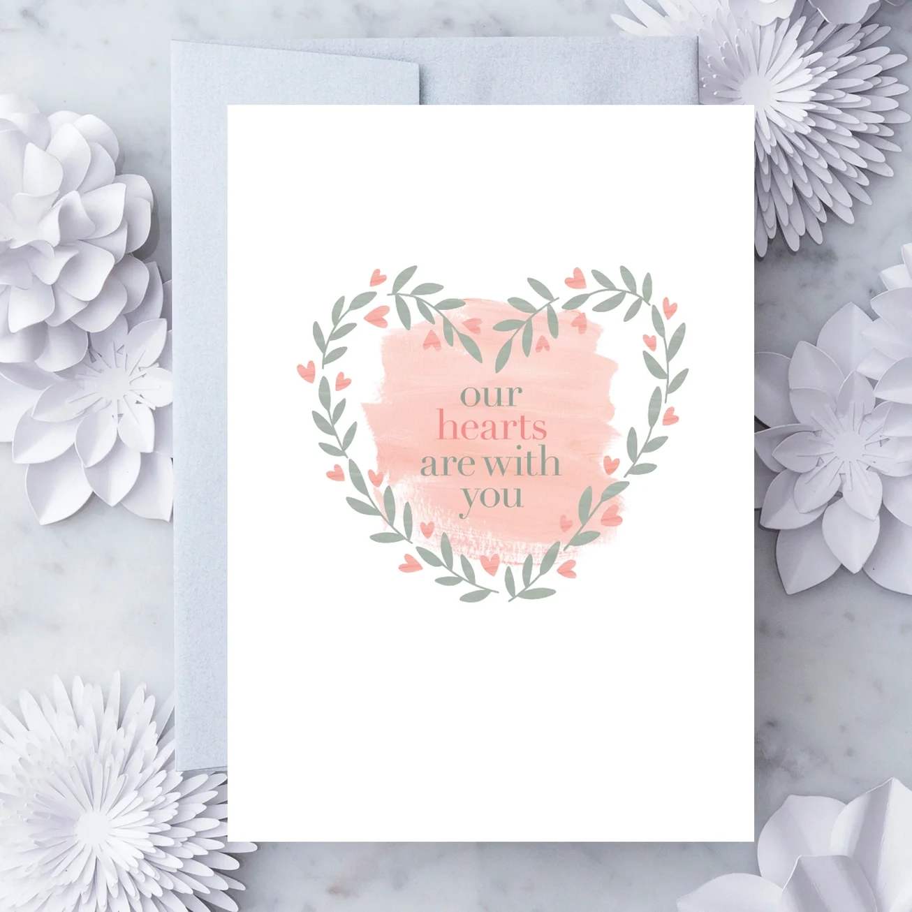 White sympathy card with peach brushstroke heart and leafy heart wreath reading 'our hearts are with you'.