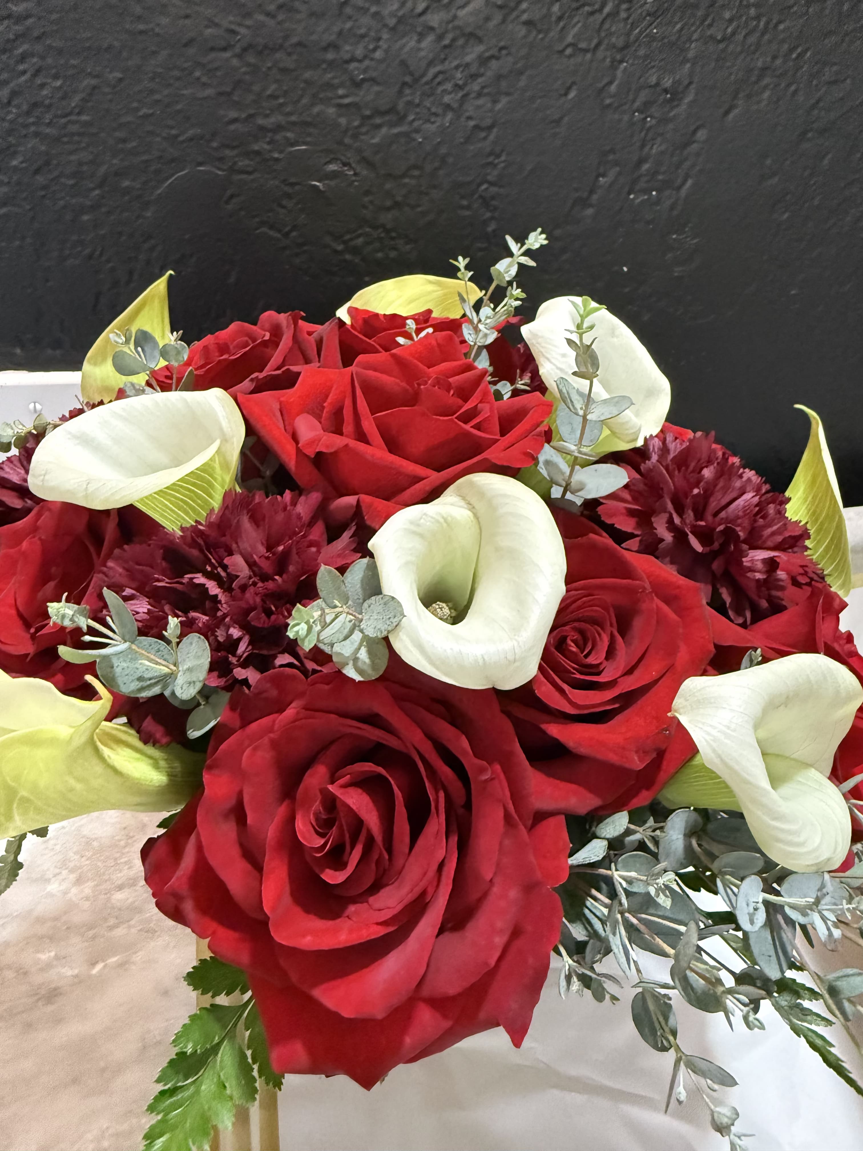 Modern Romance - A fuller design featuring red roses, a white calla lily focal bloom, and soft greenery. Graceful and refined with a classic feel.
