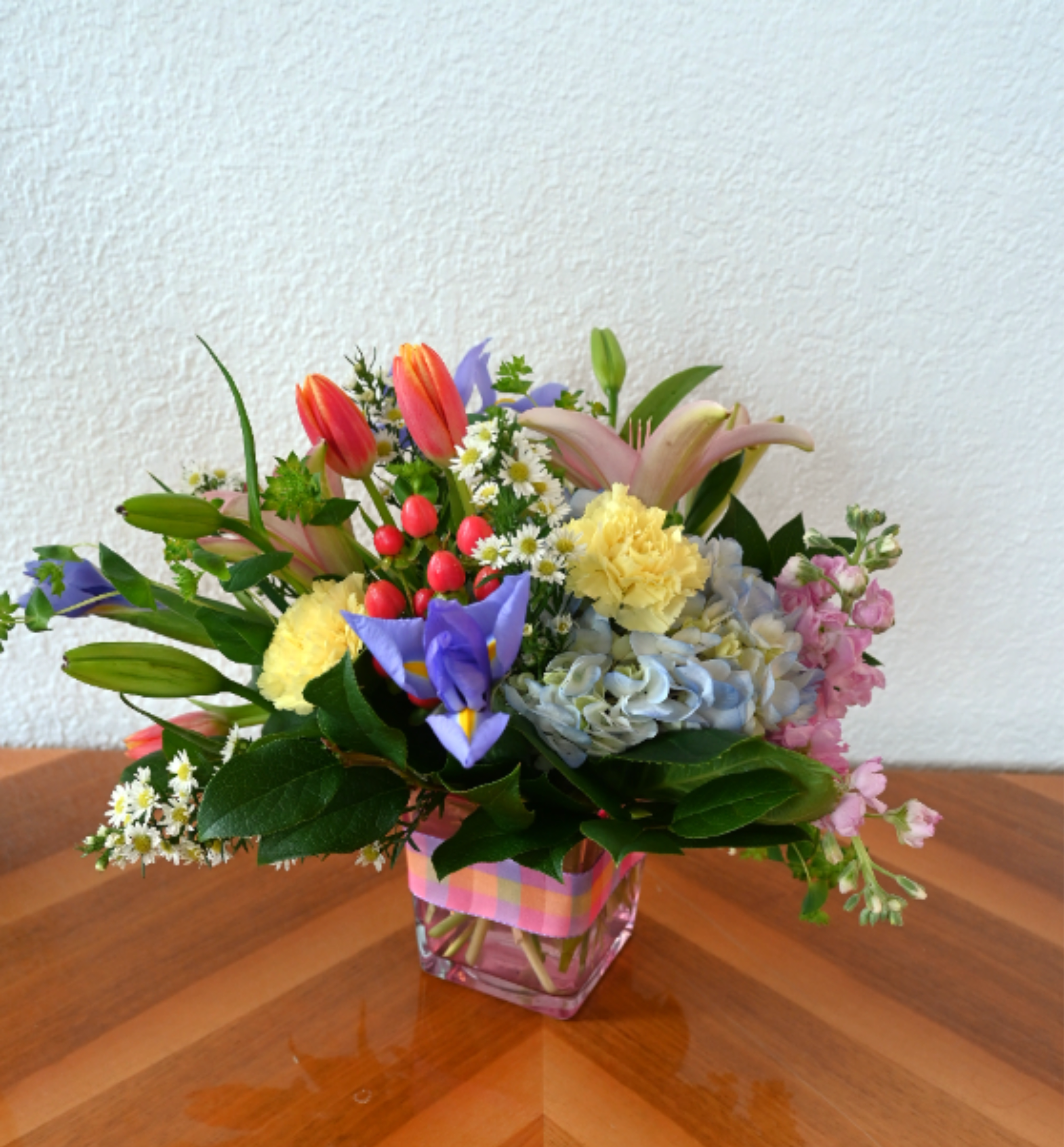 Pastel Garden - Bring the garden indoors with this delightful array of spring color! The Pastel Garden arrangement is the perfect combination of hydrangea, pink lilies, iris, tulips, and more. This lovely assortment is the perfect way to welcome spring or send them a ray of sunshine.