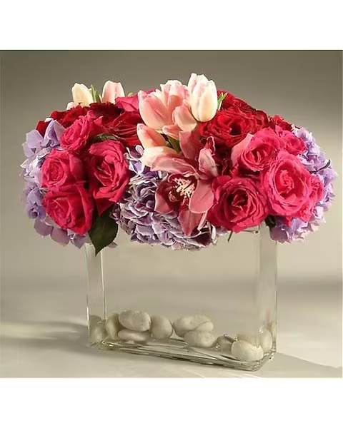 Contemporary Blast - A contemporary design consisting of hydrangea, roses, tulips and cymbidium orchid blossoms topped off with river stones in the vase to create that natural feel.