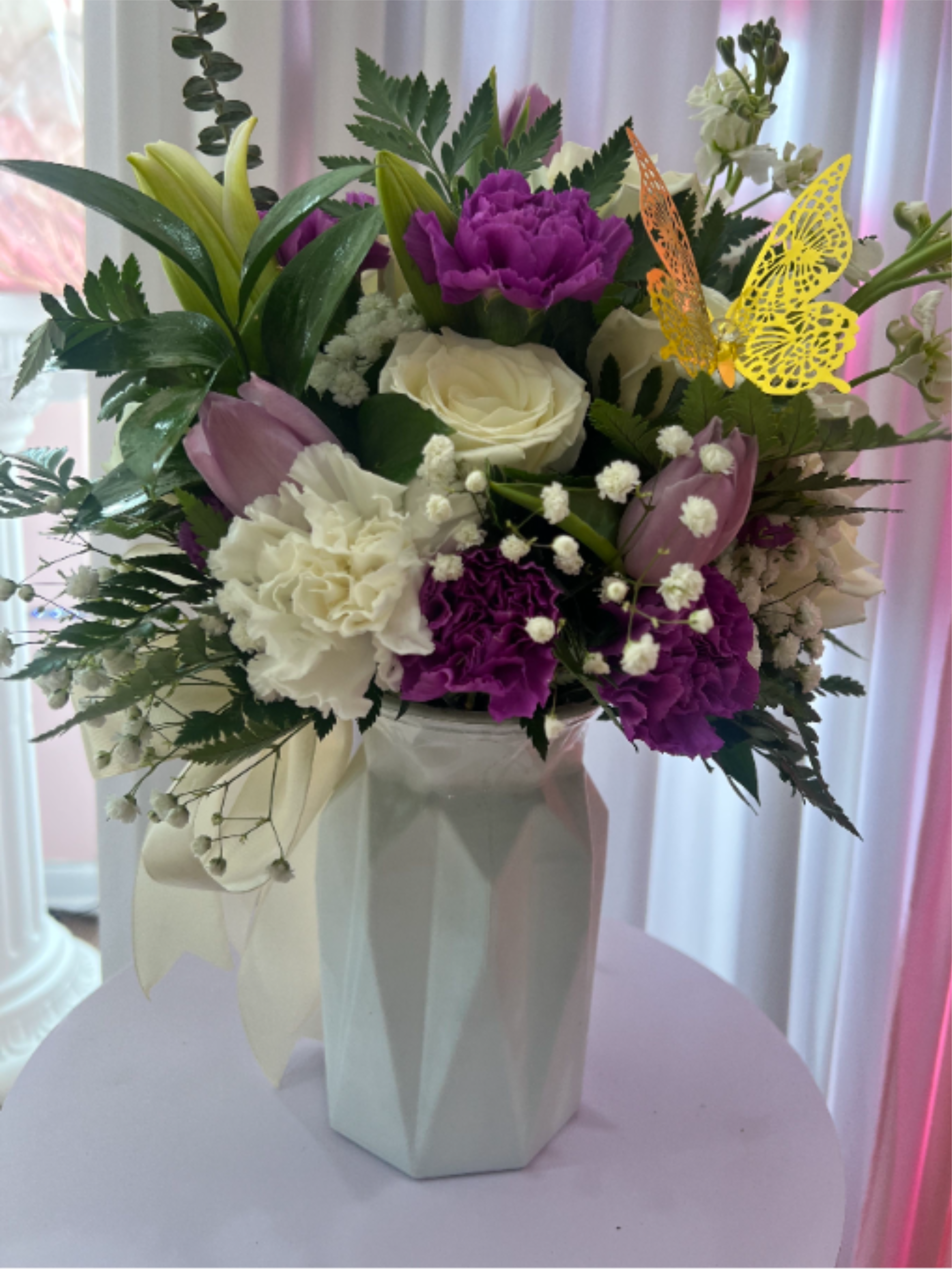 Pueple Armony - A delicate and sophisticated floral arrangement in shades of purple, lilac, and white, designed to convey elegance and harmony. Featuring a beautiful mix of tulips, carnations, roses, and lilies, complemented with fresh greenery and subtle floral accents that add texture and charm. Presented in a modern base, this arrangement is perfect for expressing love, admiration, and sweetness on any special occasion. 