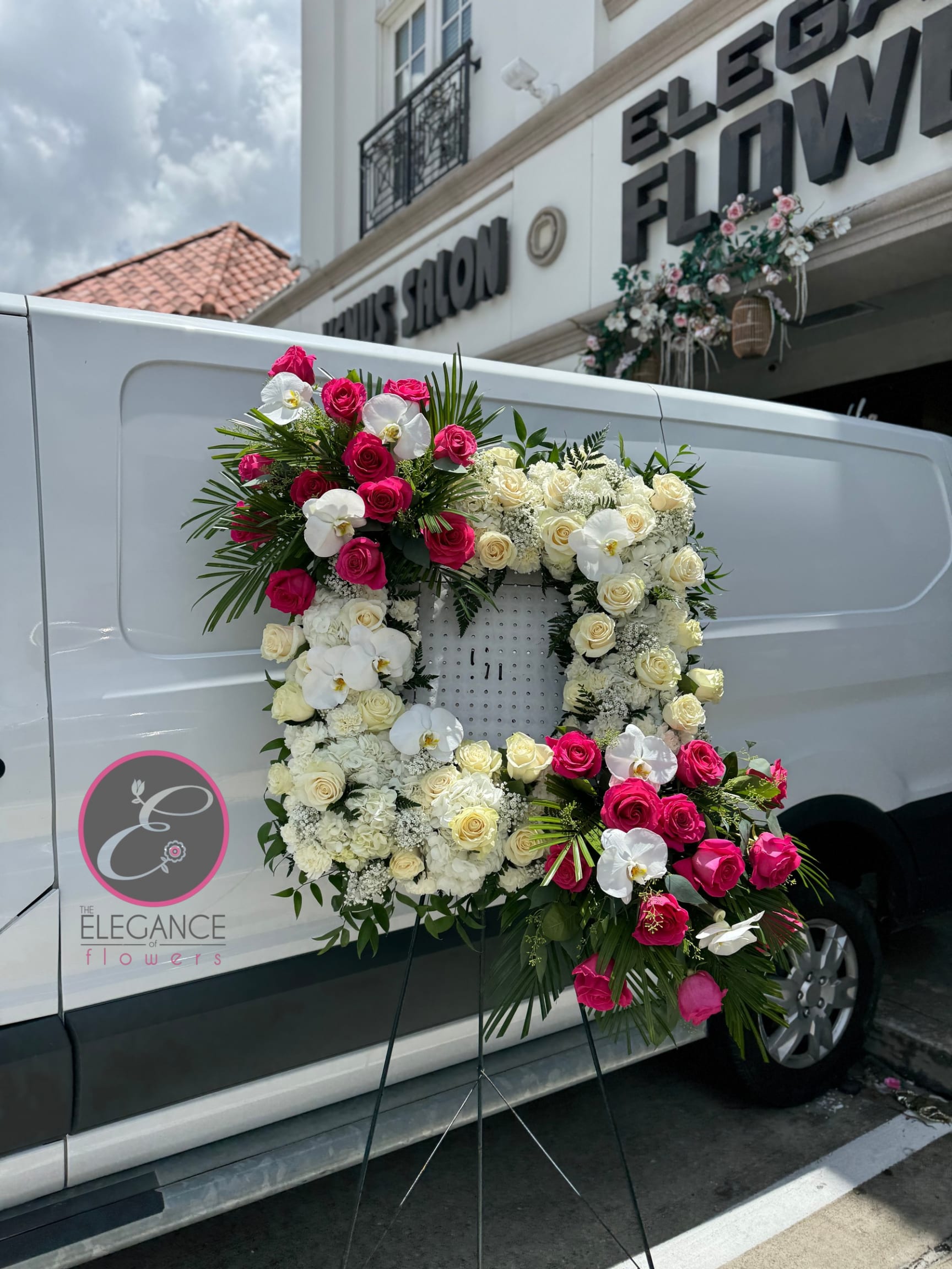 Large floral wreath on a stand with pink and white roses and orchids