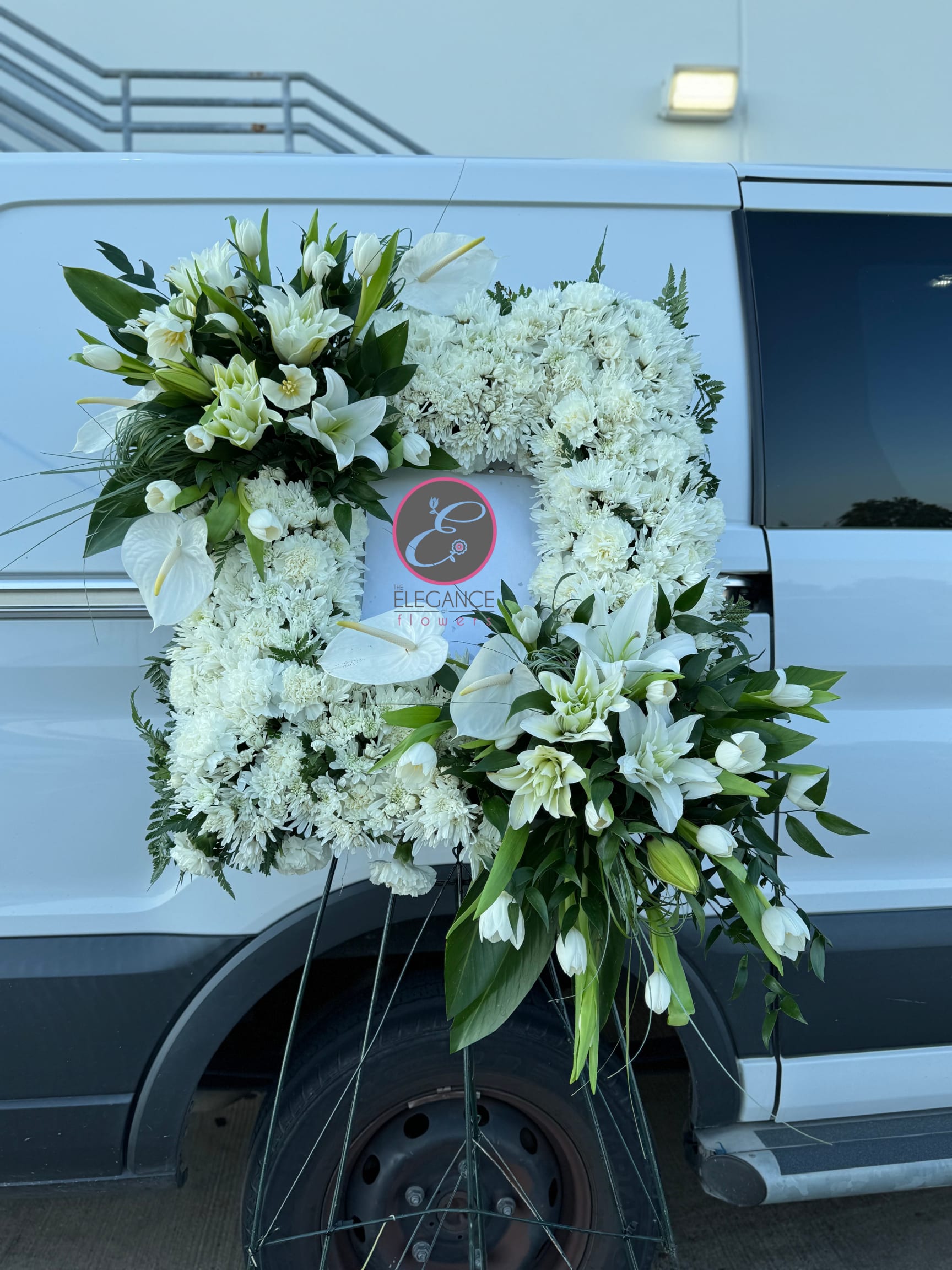 White floral funeral wreath with lilies and chrysanthemums on a stand
