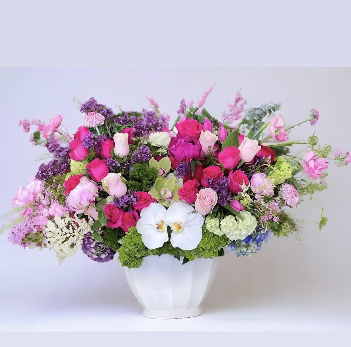 Valentino - This delightful ceramic vase arrangement features pink and hot pink Roses, Hydrangea, Phalaenopsis Orchids, and other assorted blooms