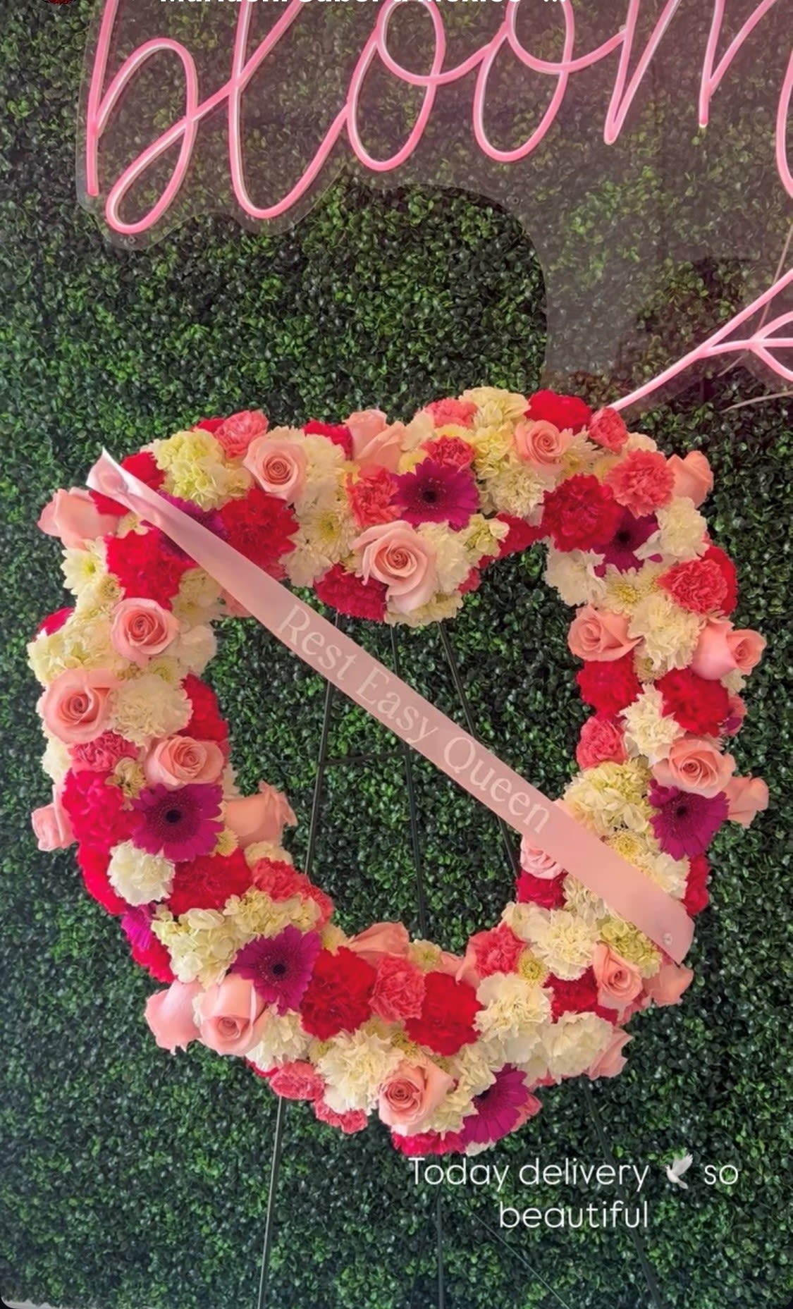 Heart Funeral Arrangement - Choose this heart standing wreath for a funeral, celebration of life, or memorial where you want the recipient to feel truly honored and loved. The metal easel is included for immediate display; for longevity, keep the arrangement cool and sheltered from direct sun until the service.  The sympathy ribbon printed with "Rest Easy Queen" drapes across the composition, giving the piece a personalized, tender message that helps the person you're honoring feel remembered and cherished.