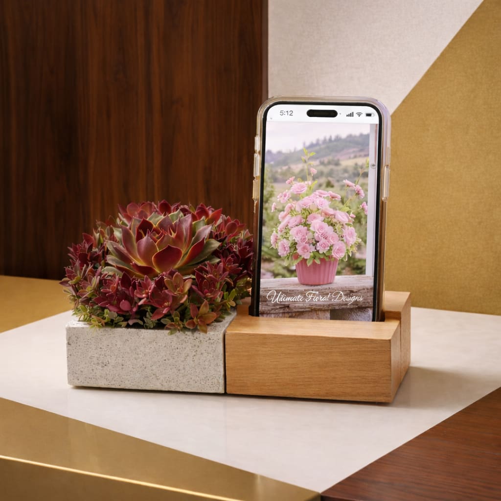 Moderno - A refined study in form and structure, Forma is a modern succulent arrangement designed with clean lines and sculptural balance. Featuring rich burgundy and green tones in a contemporary textured vessel, this piece brings depth, contrast, and quiet sophistication to any space.  Perfect for modern interiors, bedside styling, office décor, or a distinctive gift, Forma offers a lasting alternative to traditional florals while maintaining a strong design presence.  Each arrangement is handcrafted by Ultimate Floral Designs, using premium-quality elements to ensure longevity and visual harmony.  Please note: the phone shown in the image is for styling purposes only and is not included with the arrangement.  Same-day flower delivery available in Great Falls, McLean, Vienna, Reston, Arlington, and Washington, DC.