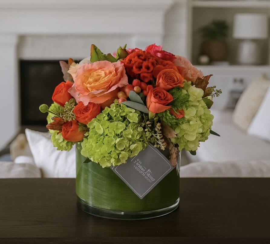 Orange and peach roses with green hydrangeas in a glass vase