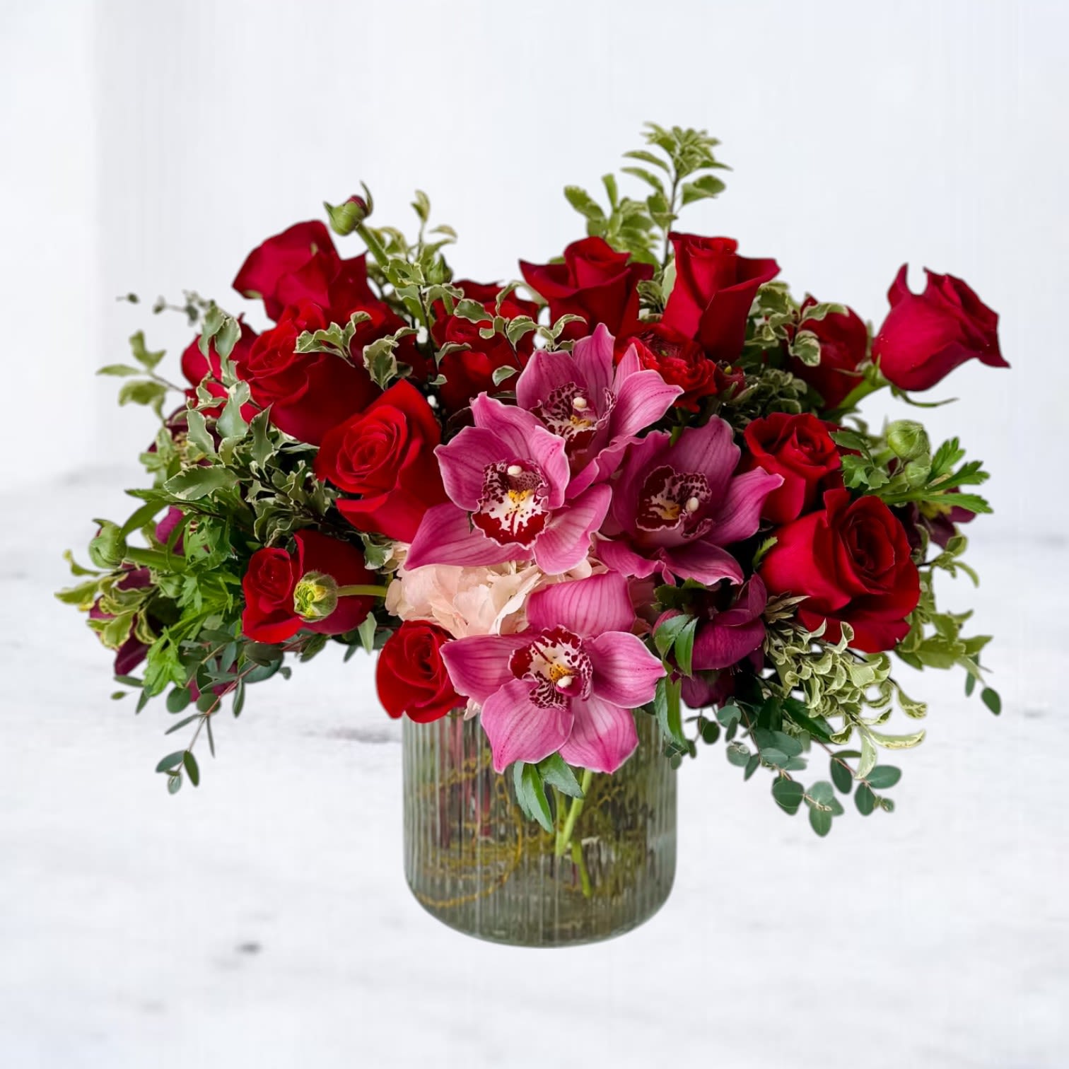 Red roses and pink orchids in a ribbed glass vase