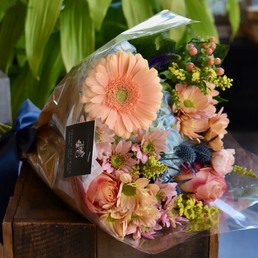 ToG Daily Wrapped Bouquets - A hand-tied bouquet featuring the freshest flowers available in our shop. Each arrangement is uniquely designed by our florists.  Please note: The image reflects size and style only. Flower types, colors, and design will vary based on seasonal availability. For specific requests, please include notes at checkout.