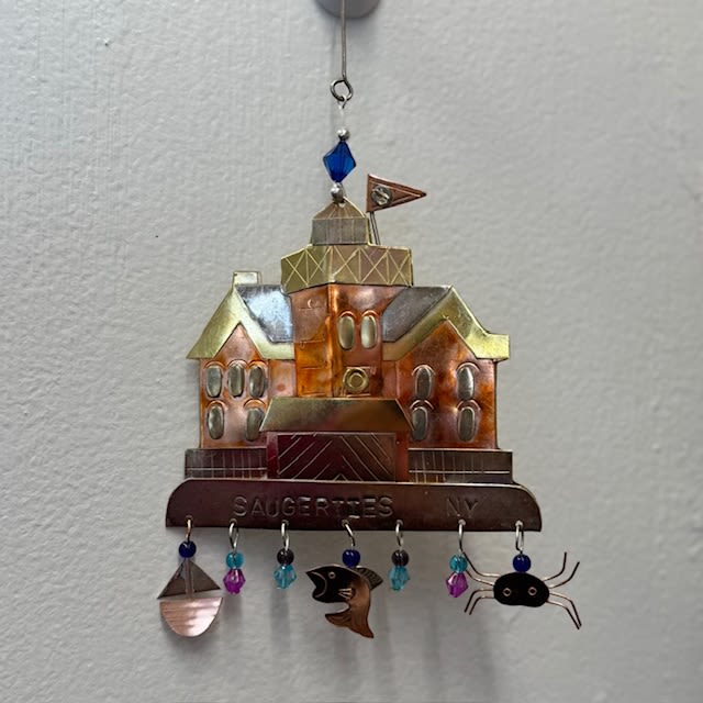 Metal wall hanging shaped like a house with dangling beads and charms