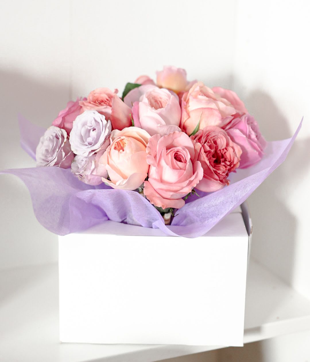 Pink and lavender rose bouquet wrapped in purple tissue paper
